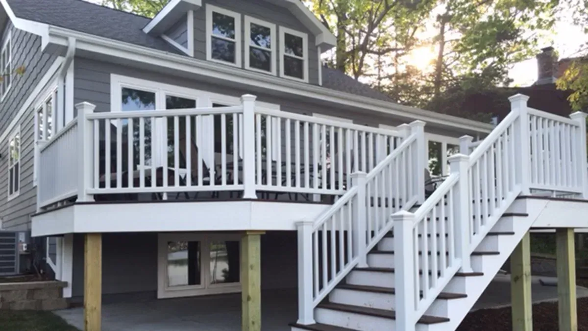 Gray house with white wraparound deck and stairs on a raised foundation