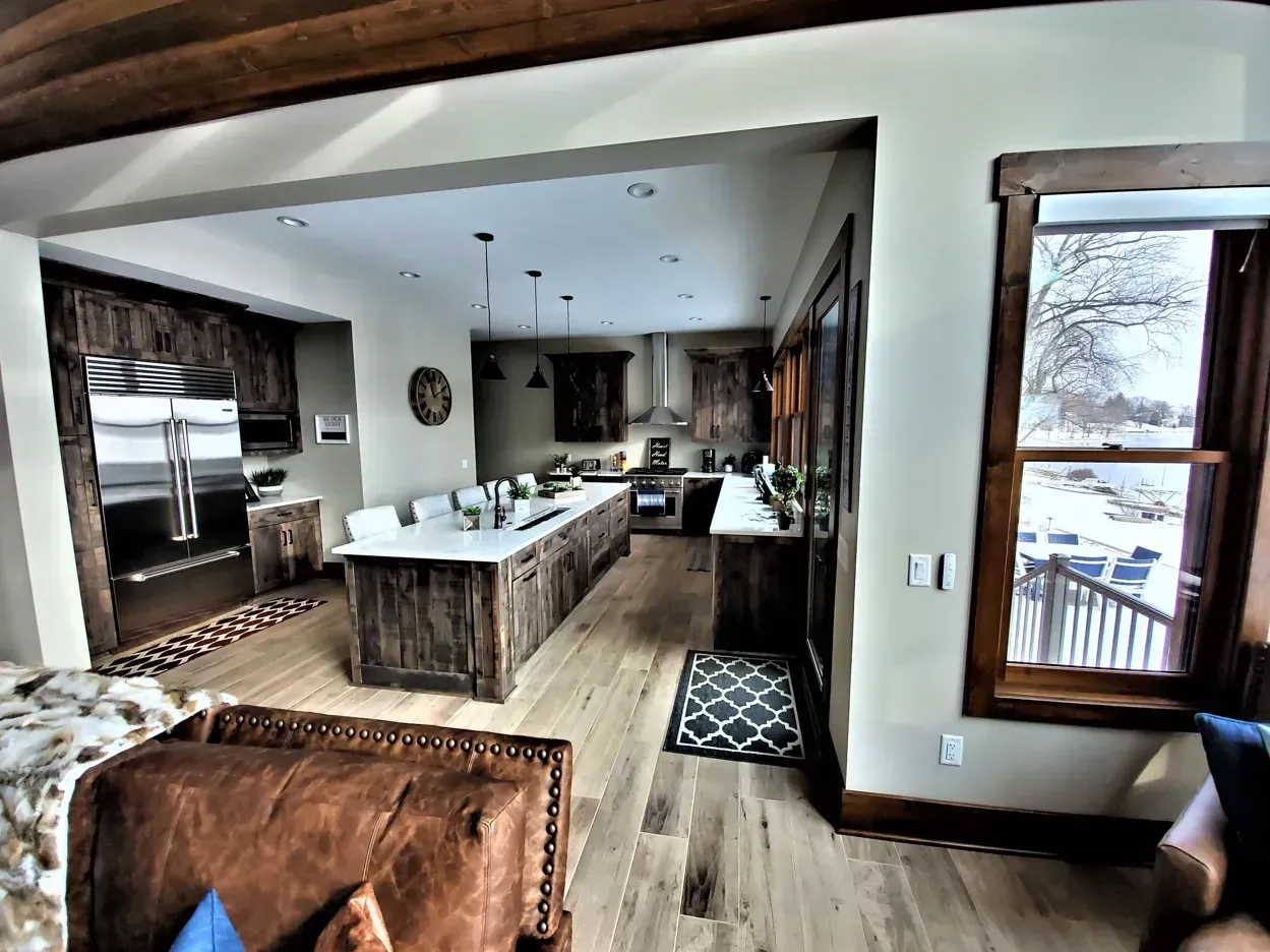 Modern kitchen with island, wood floors, and large windows showing a snowy outdoor view