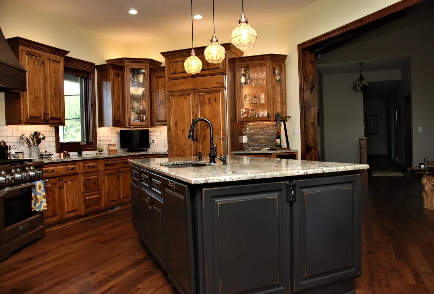 Modern kitchen with dark wood cabinets, granite island, and pendant lights