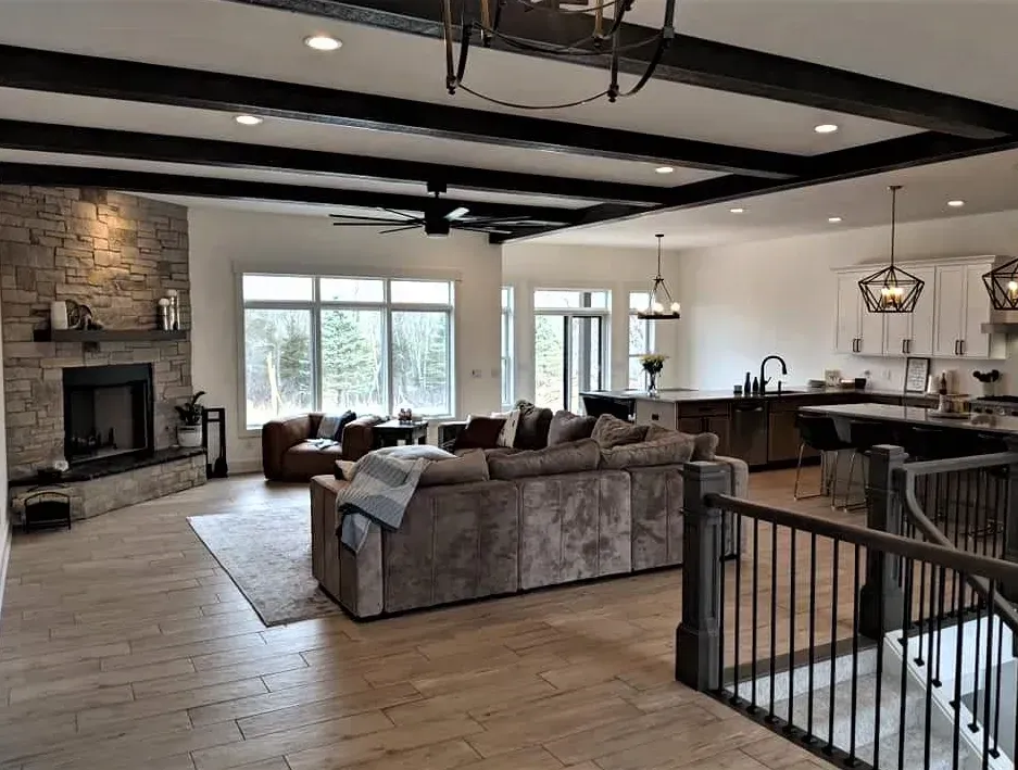 Open-concept living room with stone fireplace, sectional sofa, and kitchen island in a modern home