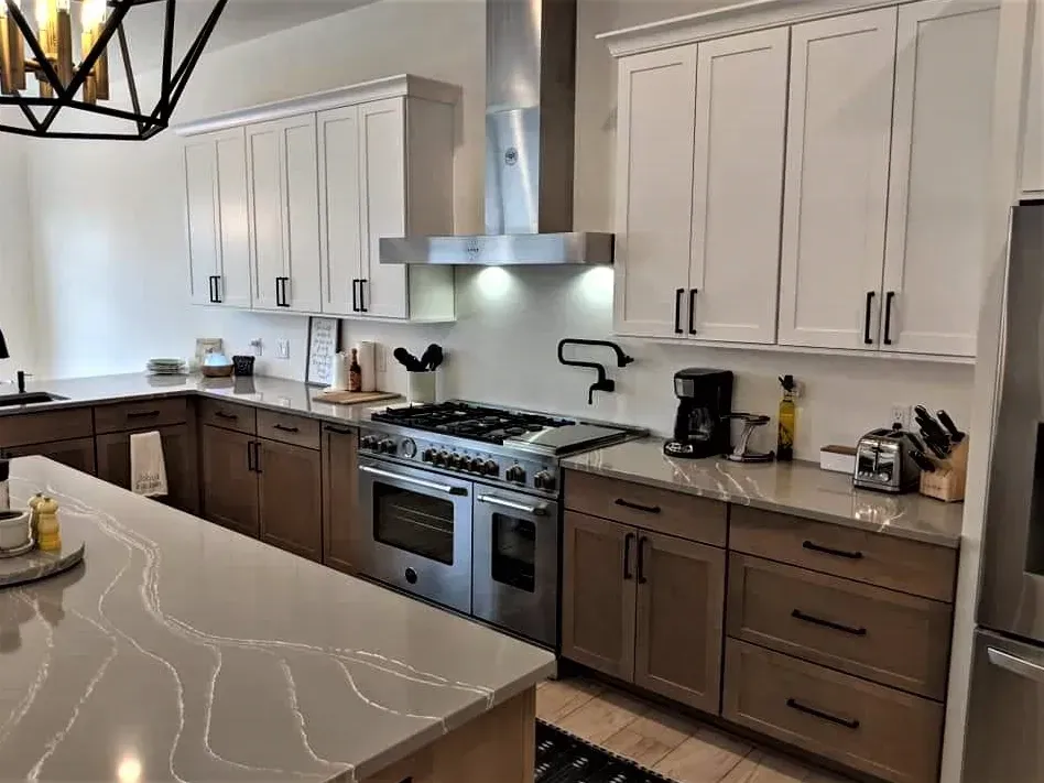 Modern kitchen with white and brown cabinets, stainless steel stove, and marble island countertop