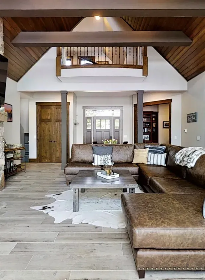 Modern living room with sectional sofa, coffee table, loft balcony, and vaulted ceiling