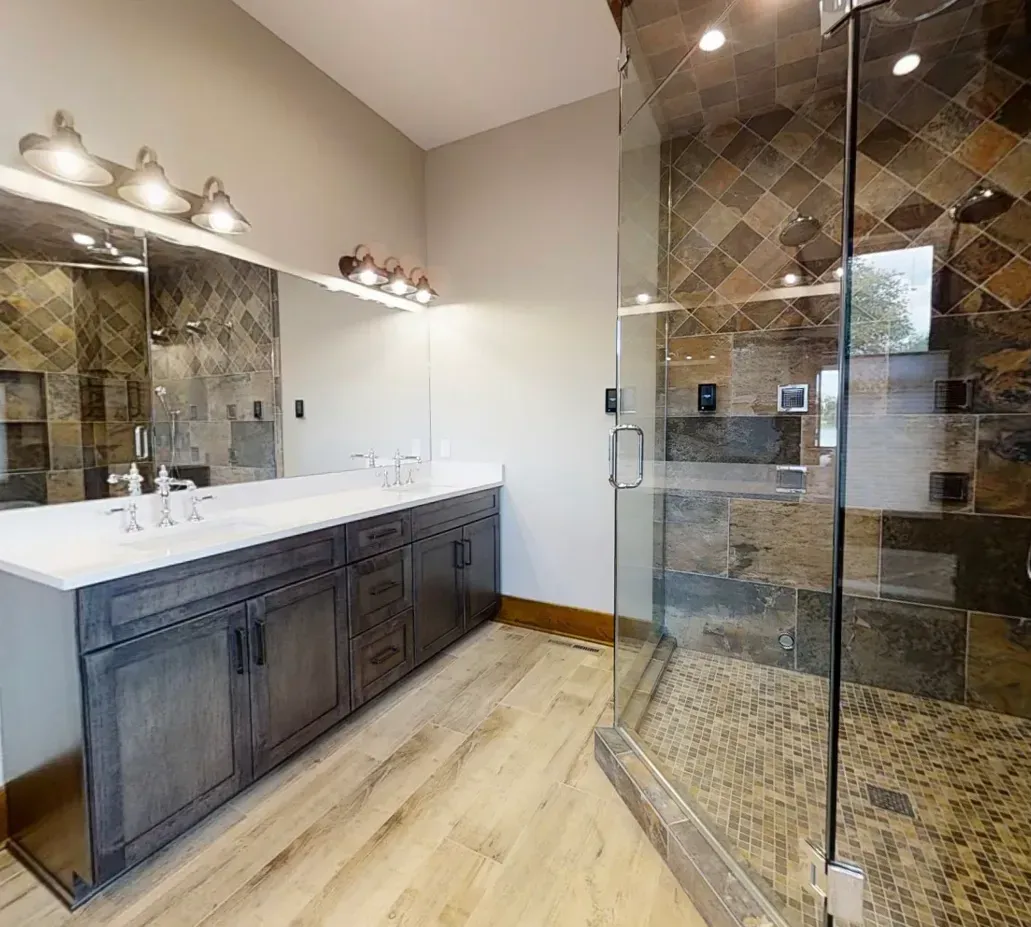 Modern bathroom with double vanity, large mirror, and glass shower enclosure