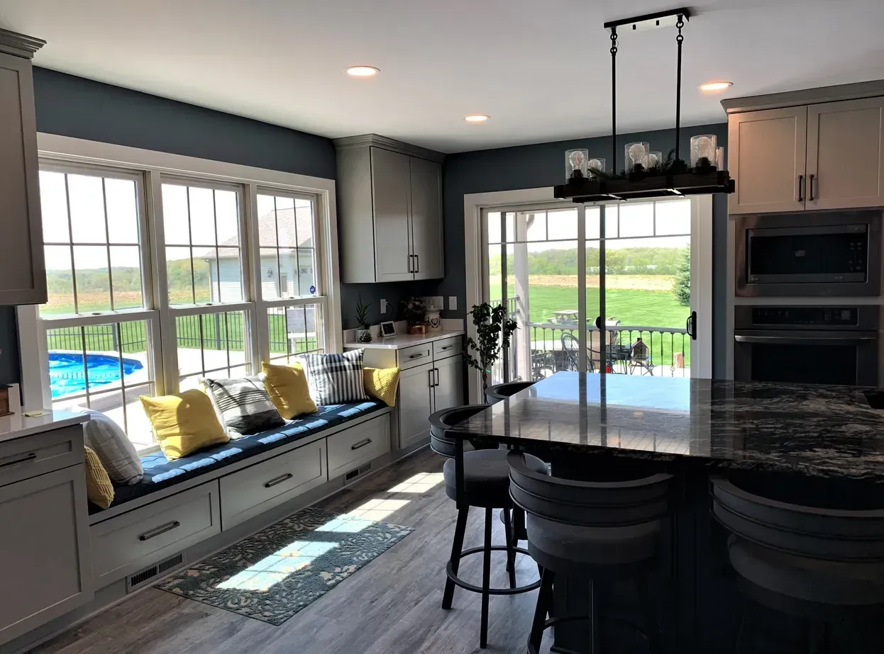 Modern kitchen with large windows, built-in bench seating, island, and a view of the pool outside