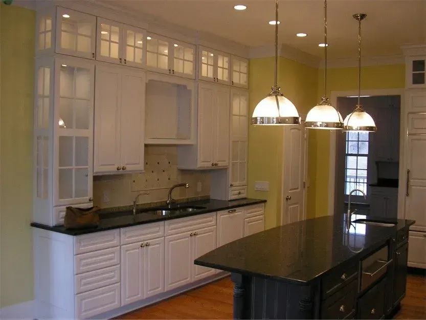 Modern kitchen with white cabinets, dark countertops, a central island, and pendant lights