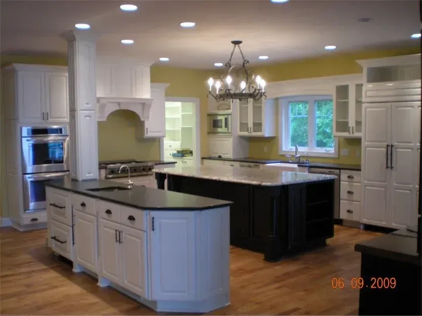 Bright kitchen with white cabinets, black island, hardwood floor, and a window over the sink