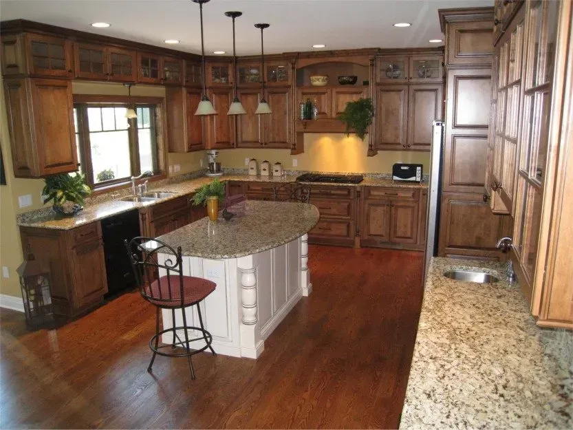 Spacious kitchen with dark wood cabinets, granite island, hardwood floors, and pendant lights