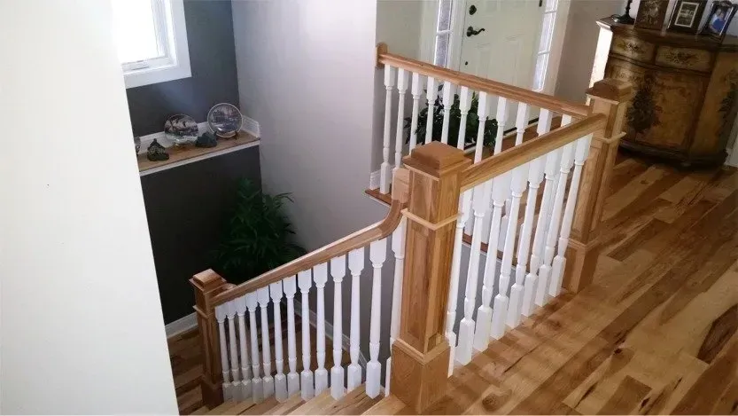 Wooden staircase with white balusters and hardwood floor in a bright home interior