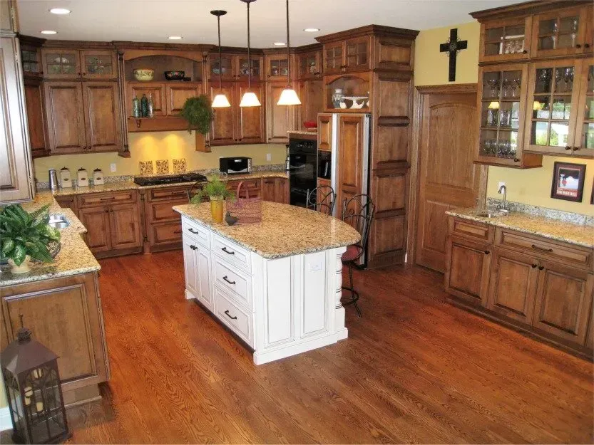 Spacious kitchen with wooden cabinets, granite island, hardwood floors, and pendant lights