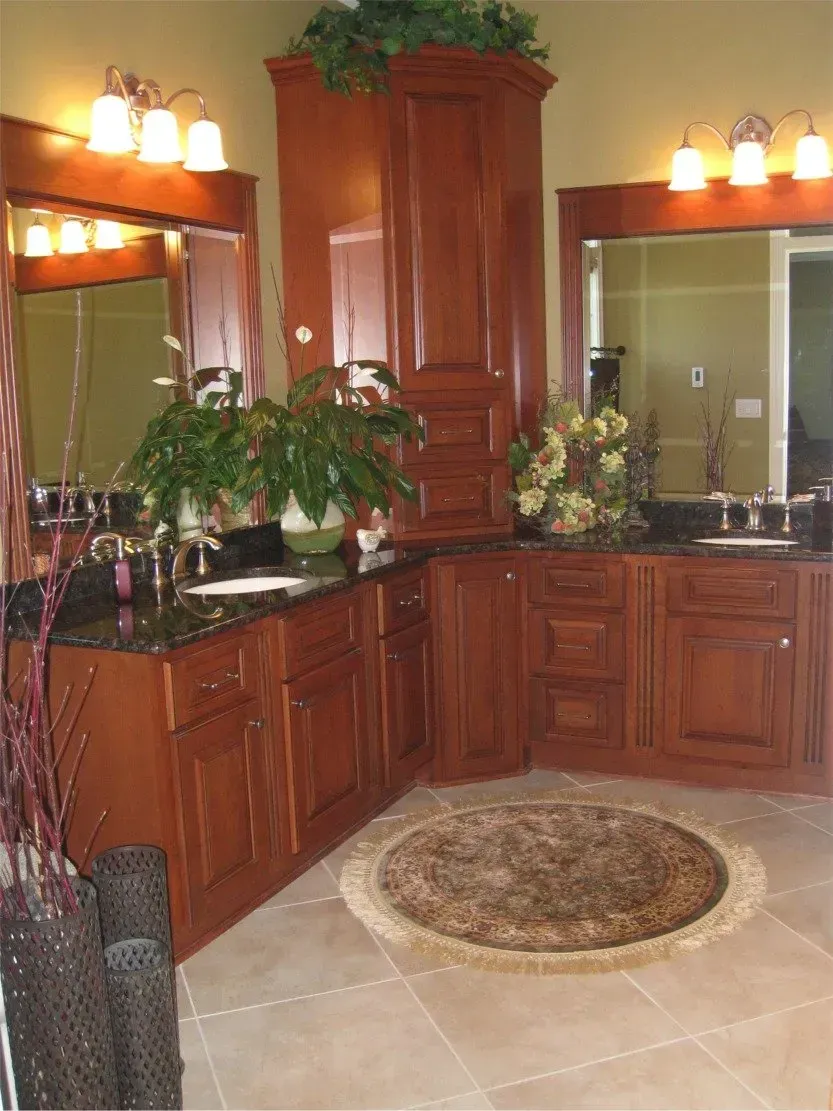 Elegant bathroom with dark wood cabinets, double mirrors, potted plants, and a round rug on tiled floor