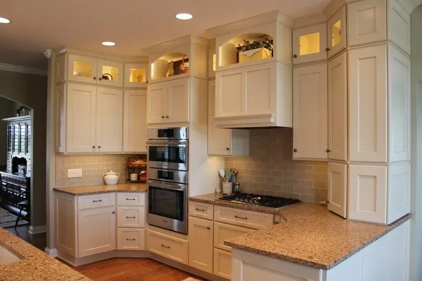 Bright white kitchen with wood cabinets, granite countertops, recessed lighting, and stainless steel appliances