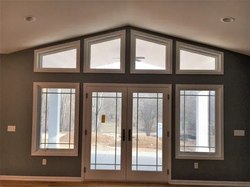 Modern entryway with tall glass double doors and triangular windows under a peaked ceiling