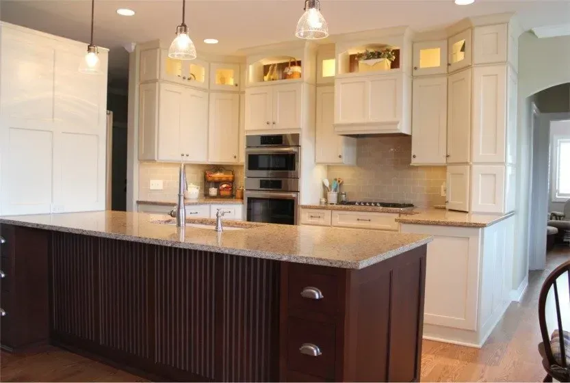 Bright white kitchen with dark wood island, pendant lights, and built-in stainless appliances