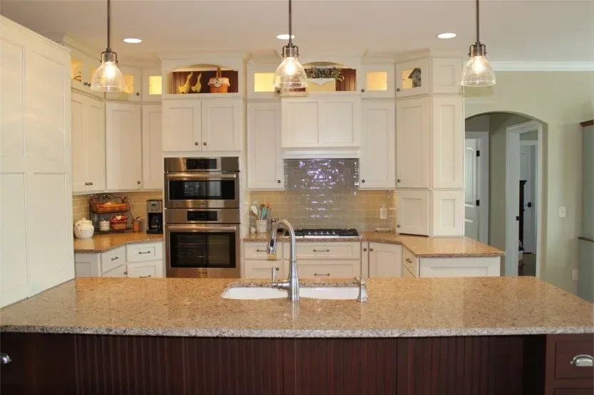 Bright modern kitchen with white cabinets, granite island, pendant lights, and stainless steel appliances