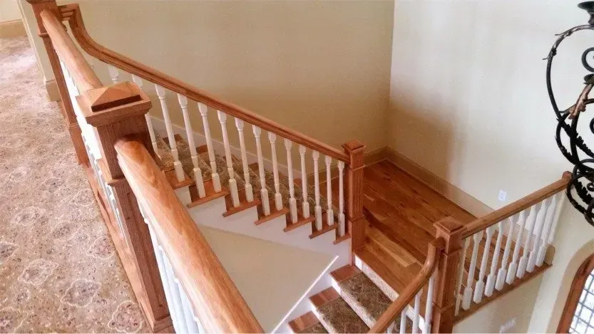 Wooden staircase with white balusters and handrail in a beige interior hallway