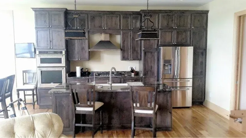 Kitchen with dark wood cabinets, stainless appliances, and a breakfast bar with stools.