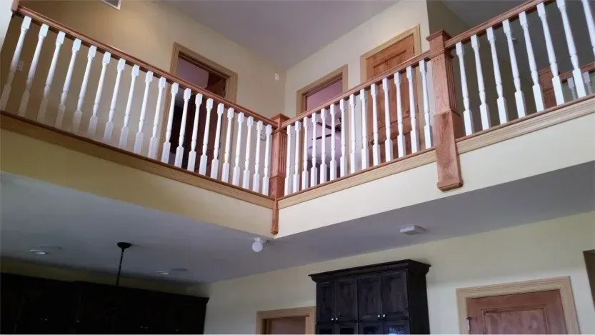 Interior view of a home with a second-floor wooden railing overlooking a room below