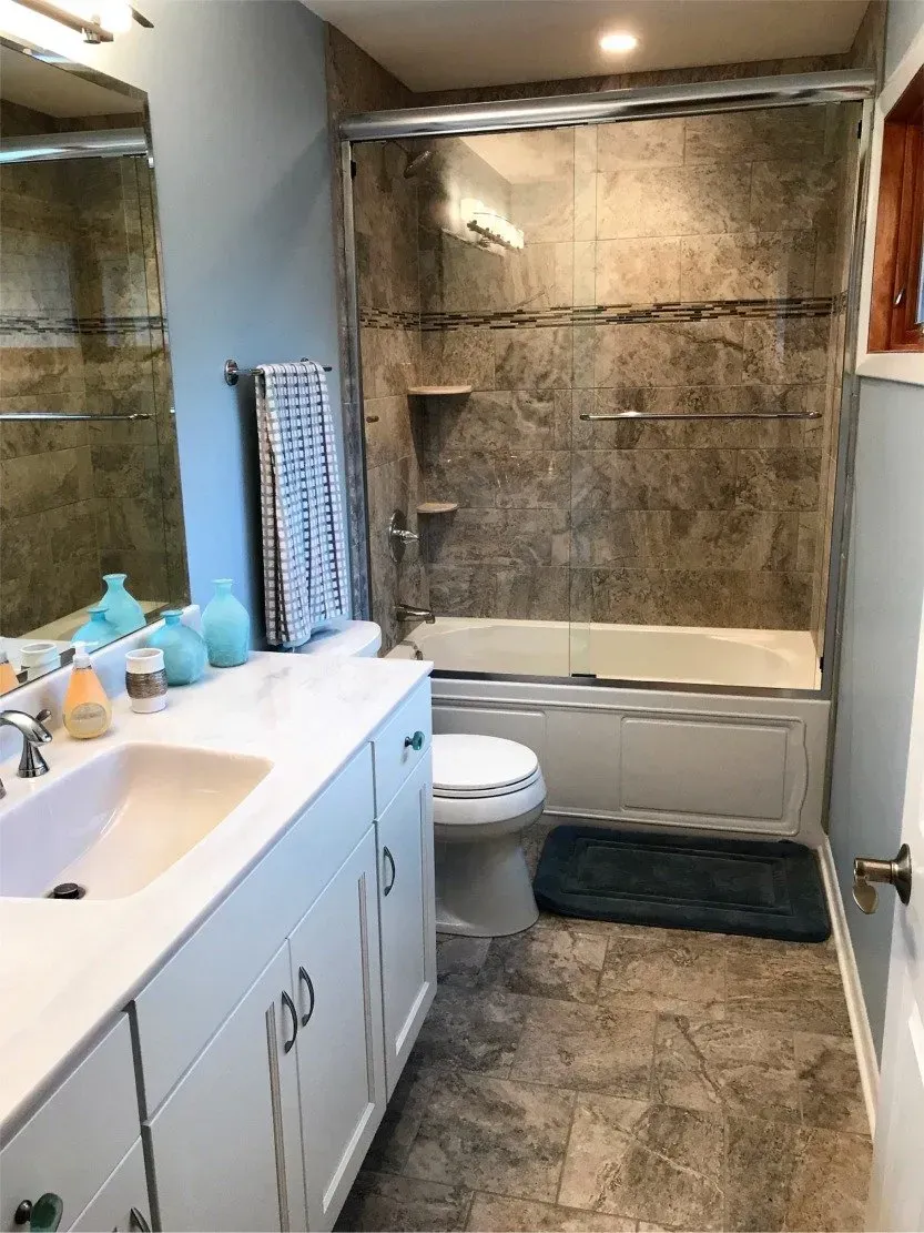 Bathroom with sink, vanity, toilet, and a tiled shower area covered in plastic or insulation.
