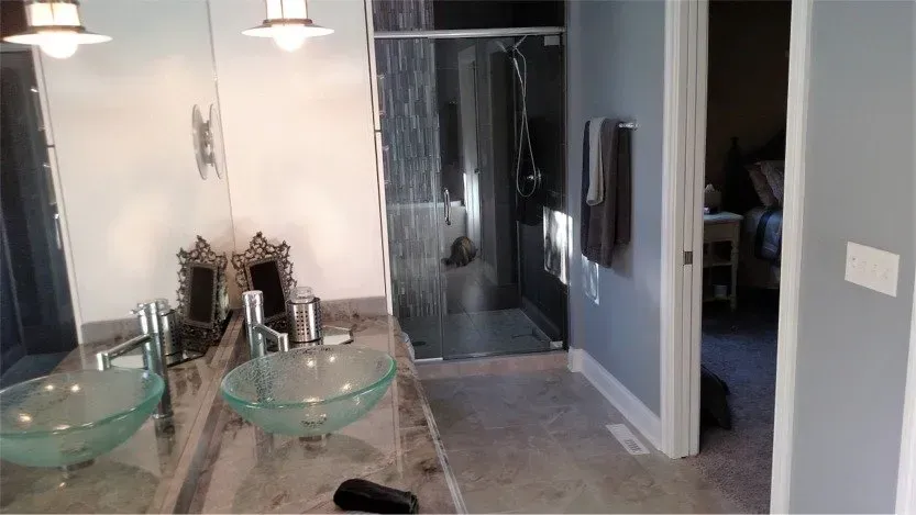 Modern bathroom with glass sink, large mirror, shower, and gray walls