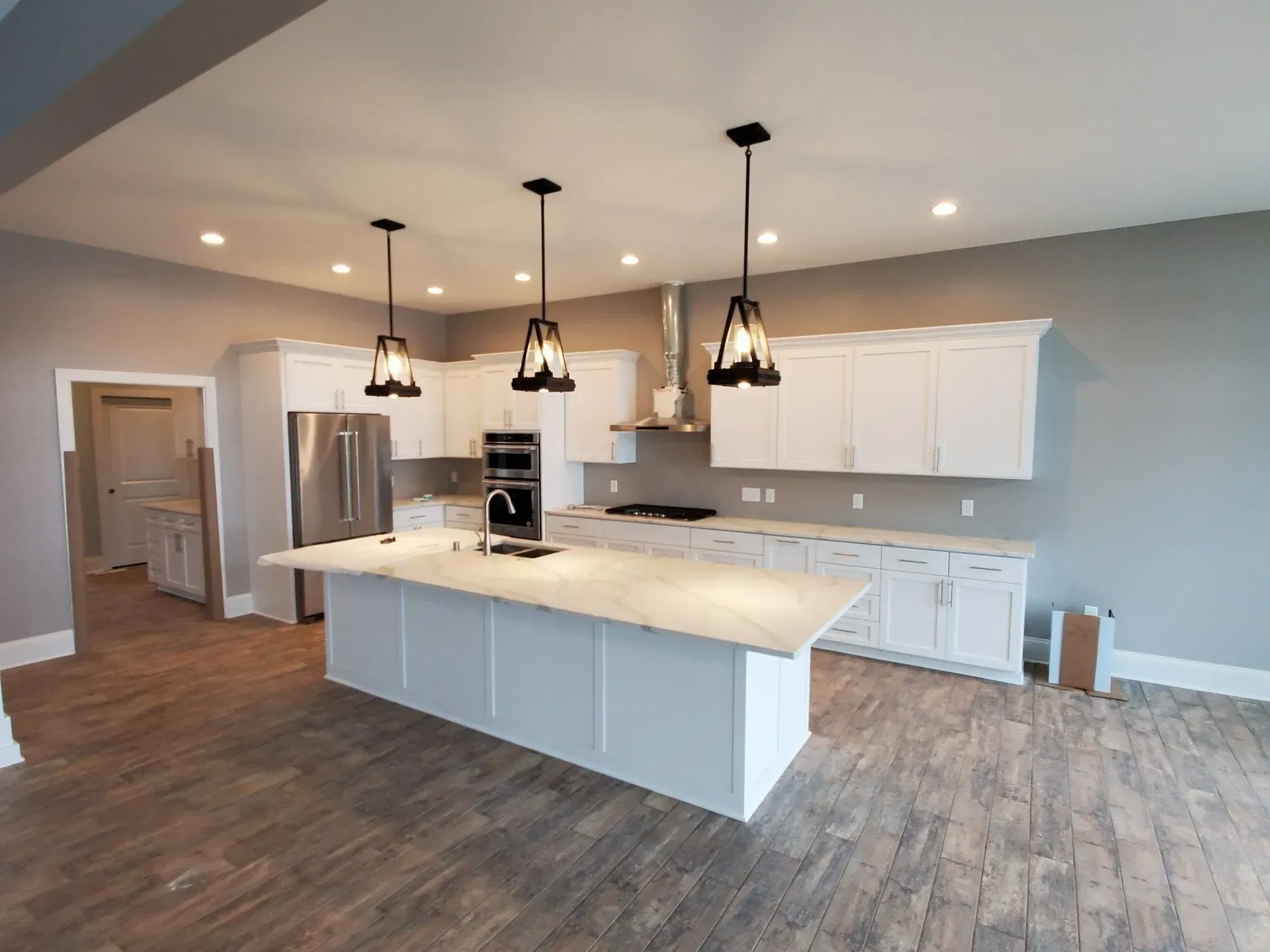 Modern kitchen with white cabinets, large island, stainless appliances, and wood flooring in an open floor plan