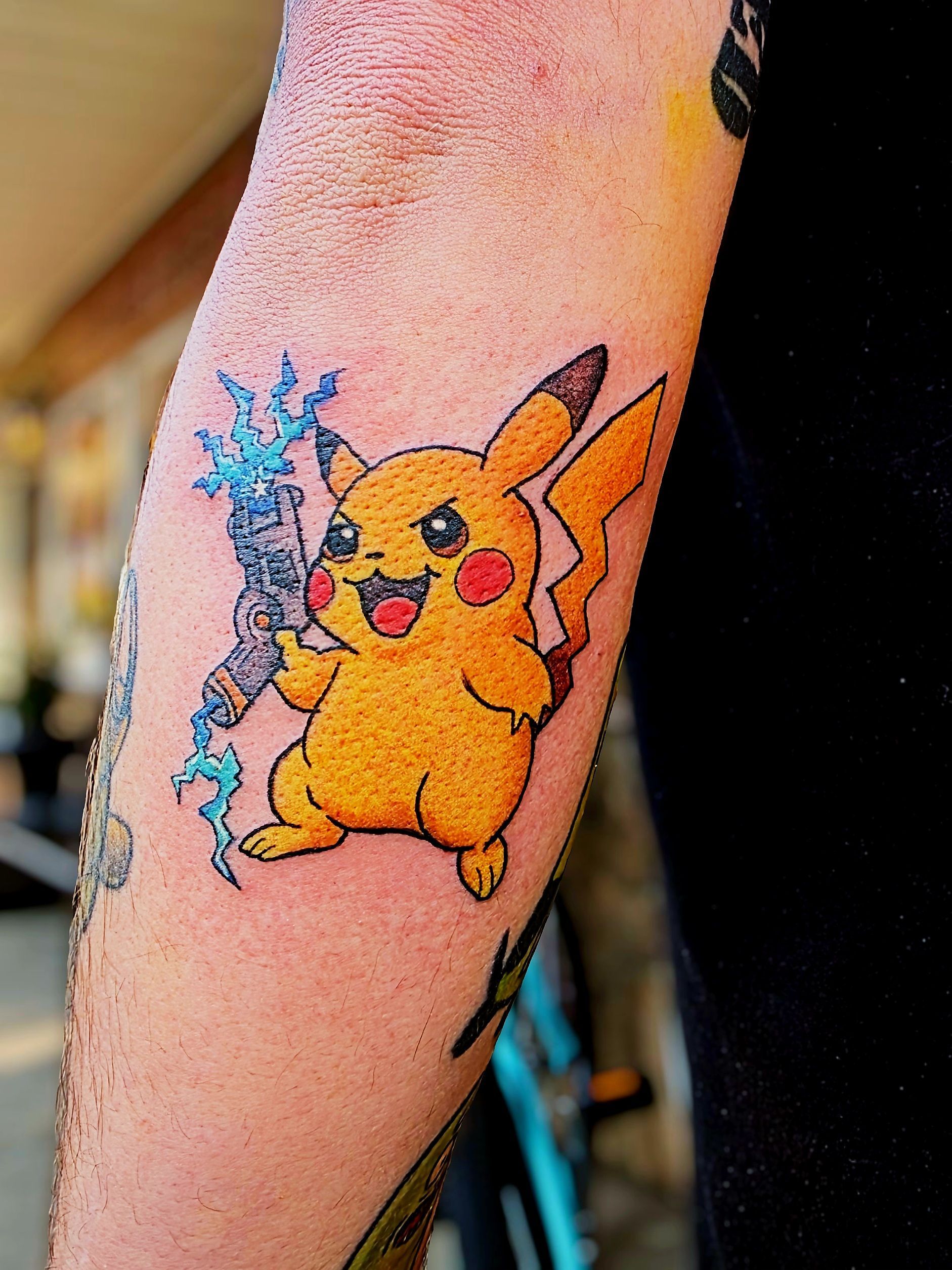 Pikachu tattoo on an arm, holding blue lightning, with a slightly angry expression.