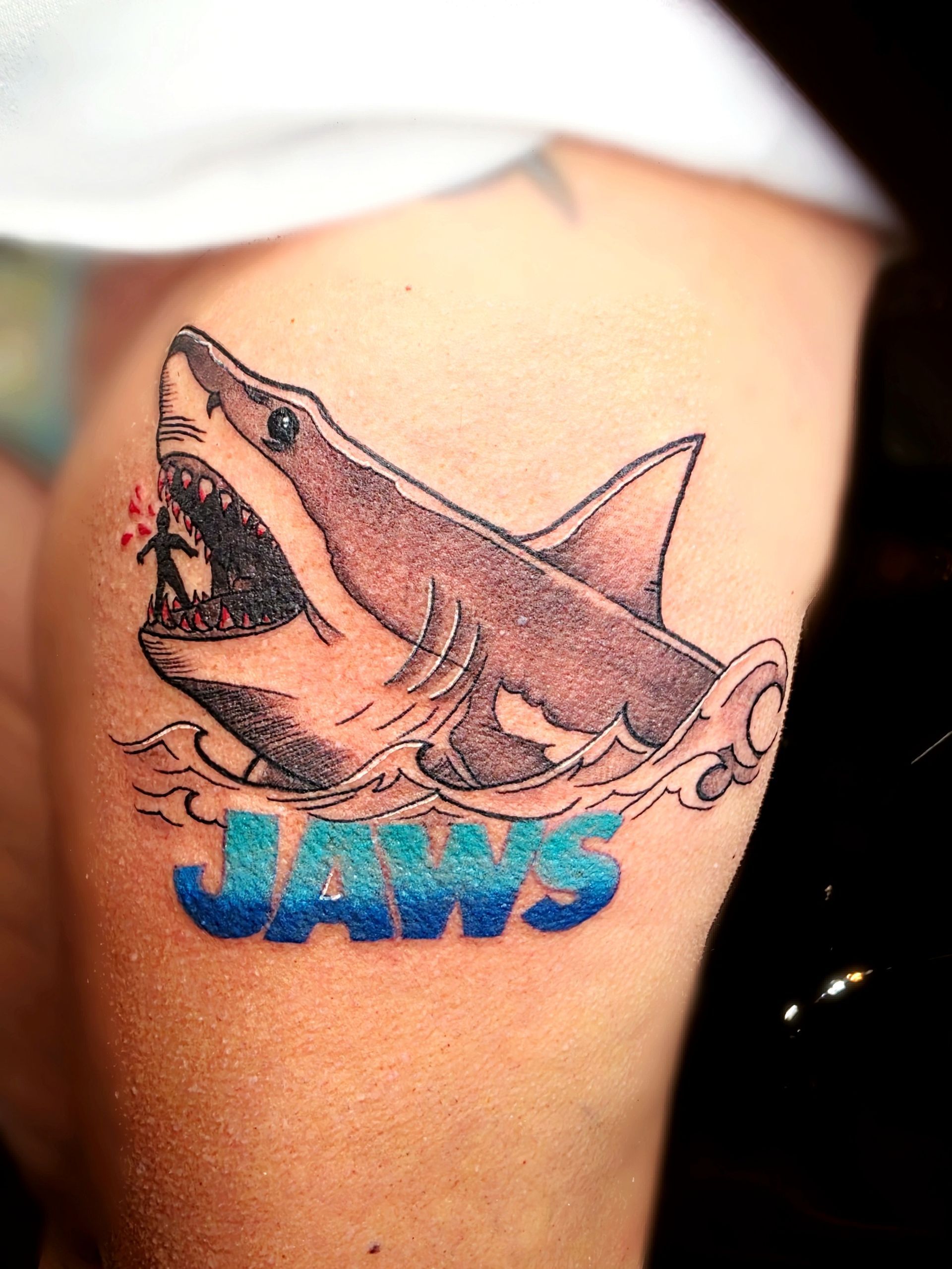 Shark tattoo with open jaws, waves, and 