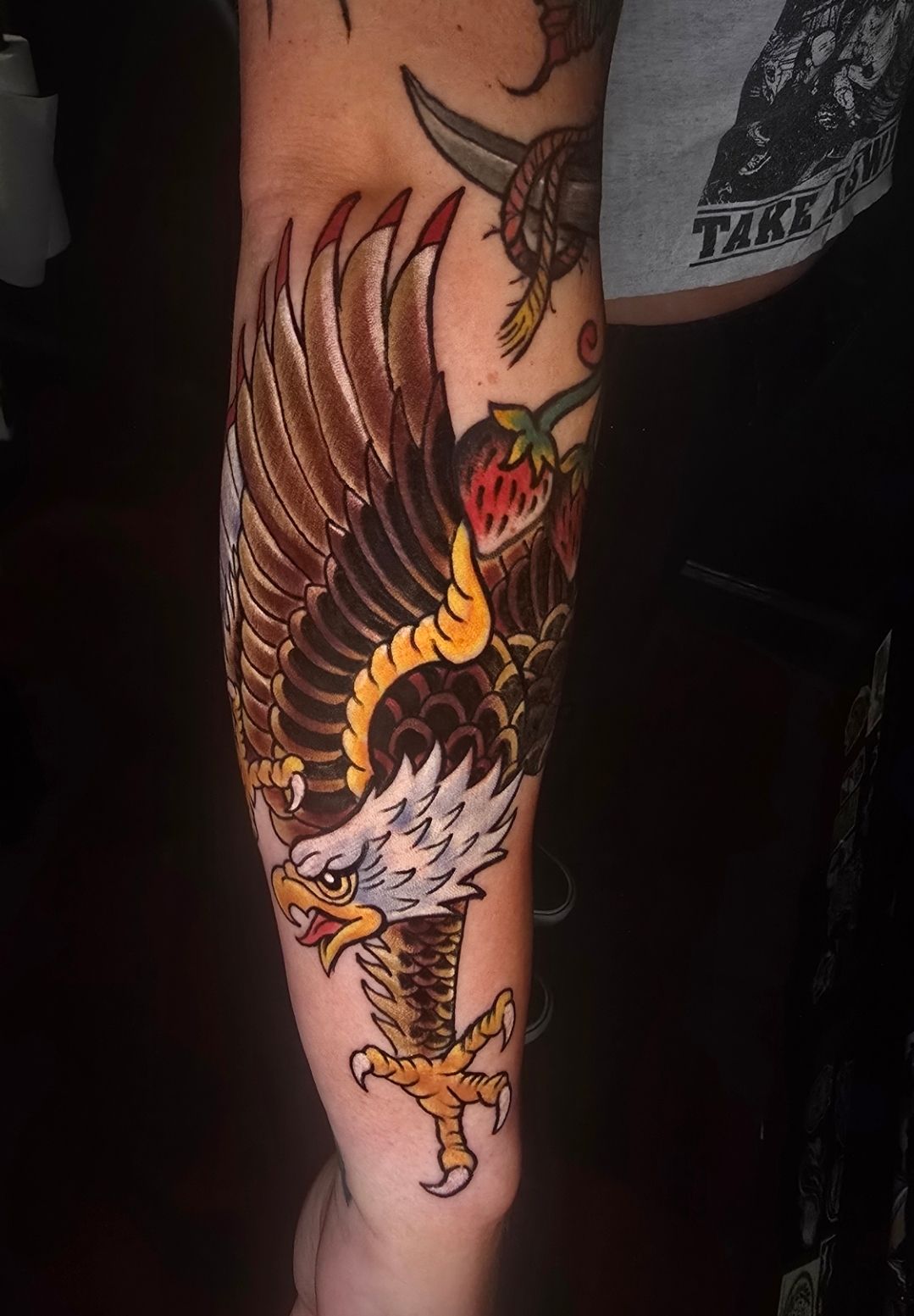 Tattoo of a bald eagle with outstretched wings on an arm, brown, white, and yellow colors.