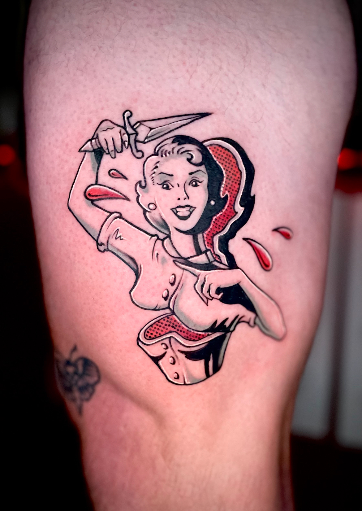 Tattoo of a woman in a vintage style, holding a knife and cutting open her torso; red and black ink.