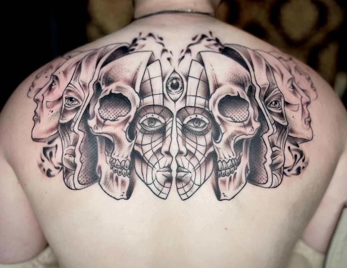 Back tattoo featuring skulls and stylized faces in black ink.