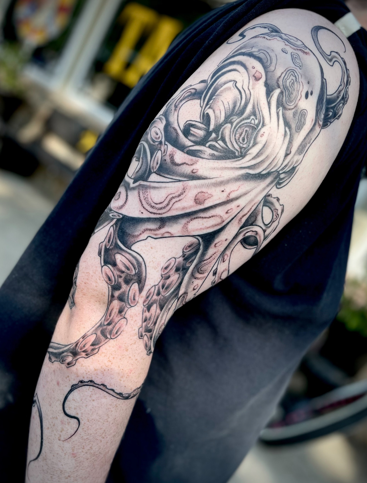 Black and gray octopus tattoo on a person's upper arm.