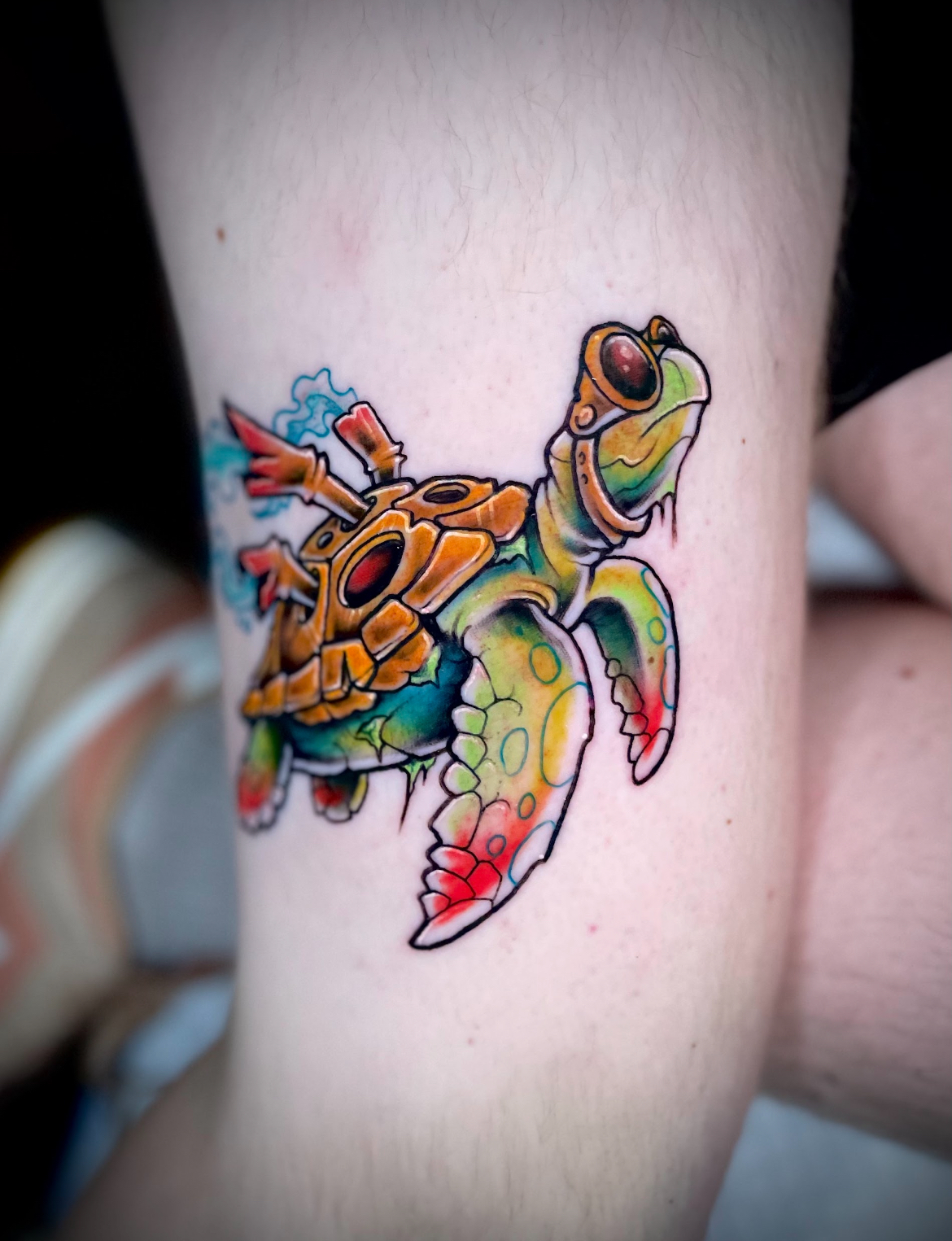 Colorful turtle tattoo on a leg. The turtle has steampunk elements and is in vibrant colors.