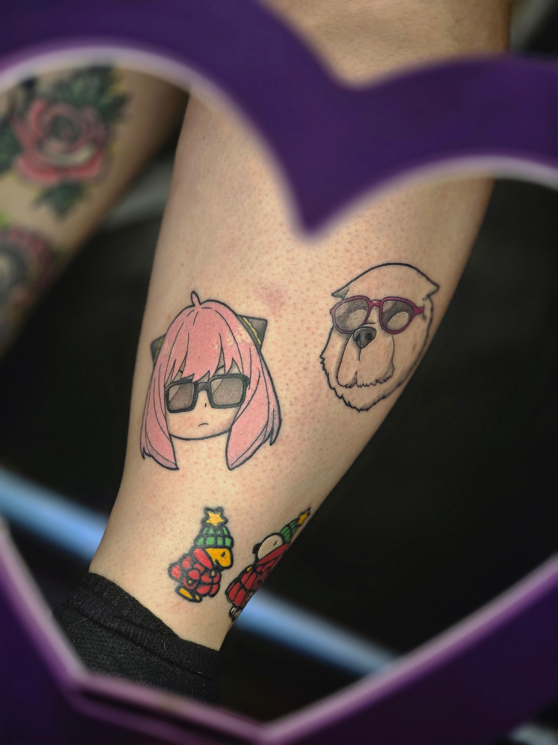 Tattoos of Anya Forger and Bond Forger from Spy x Family, wearing sunglasses.  A holiday bird is also tattooed.