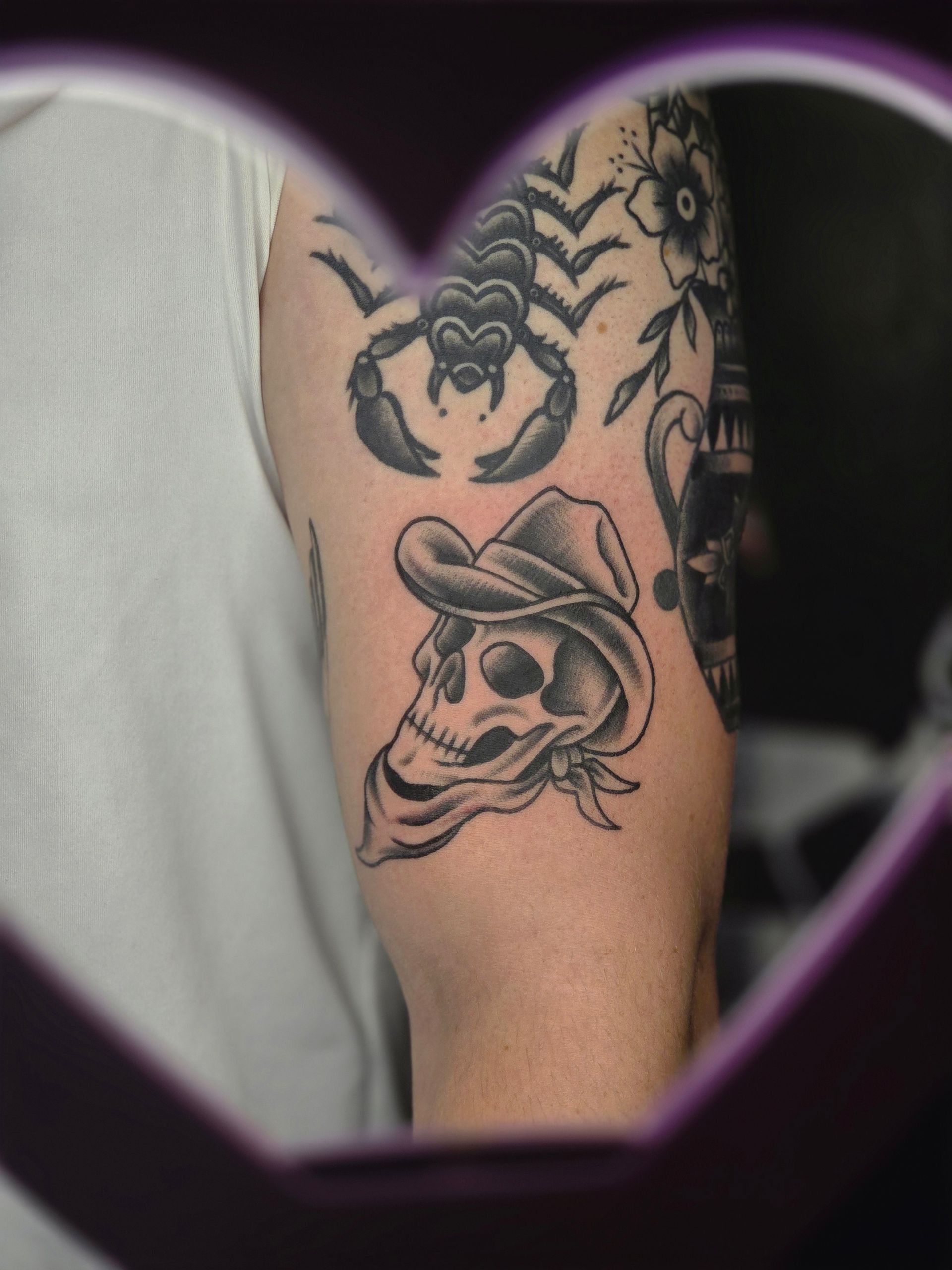 Tattoo of a skull wearing a cowboy hat and bandana. Other tattoos visible, including a scorpion.