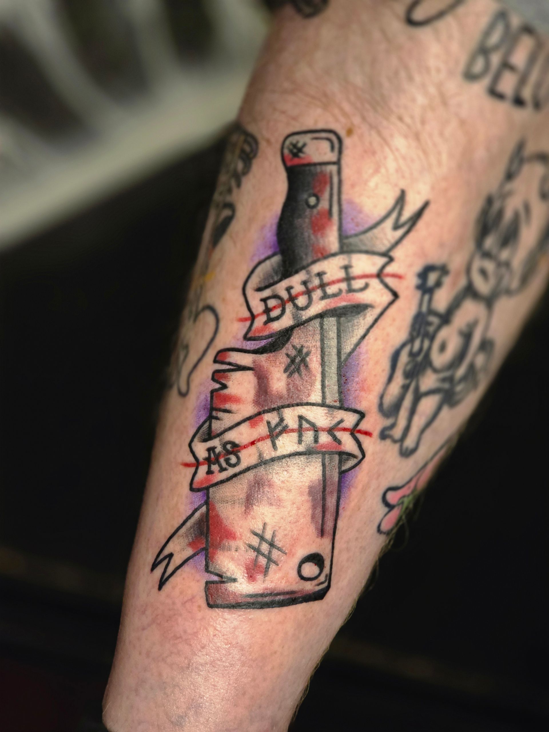 Tattoo of a bloody cleaver with banner reading 