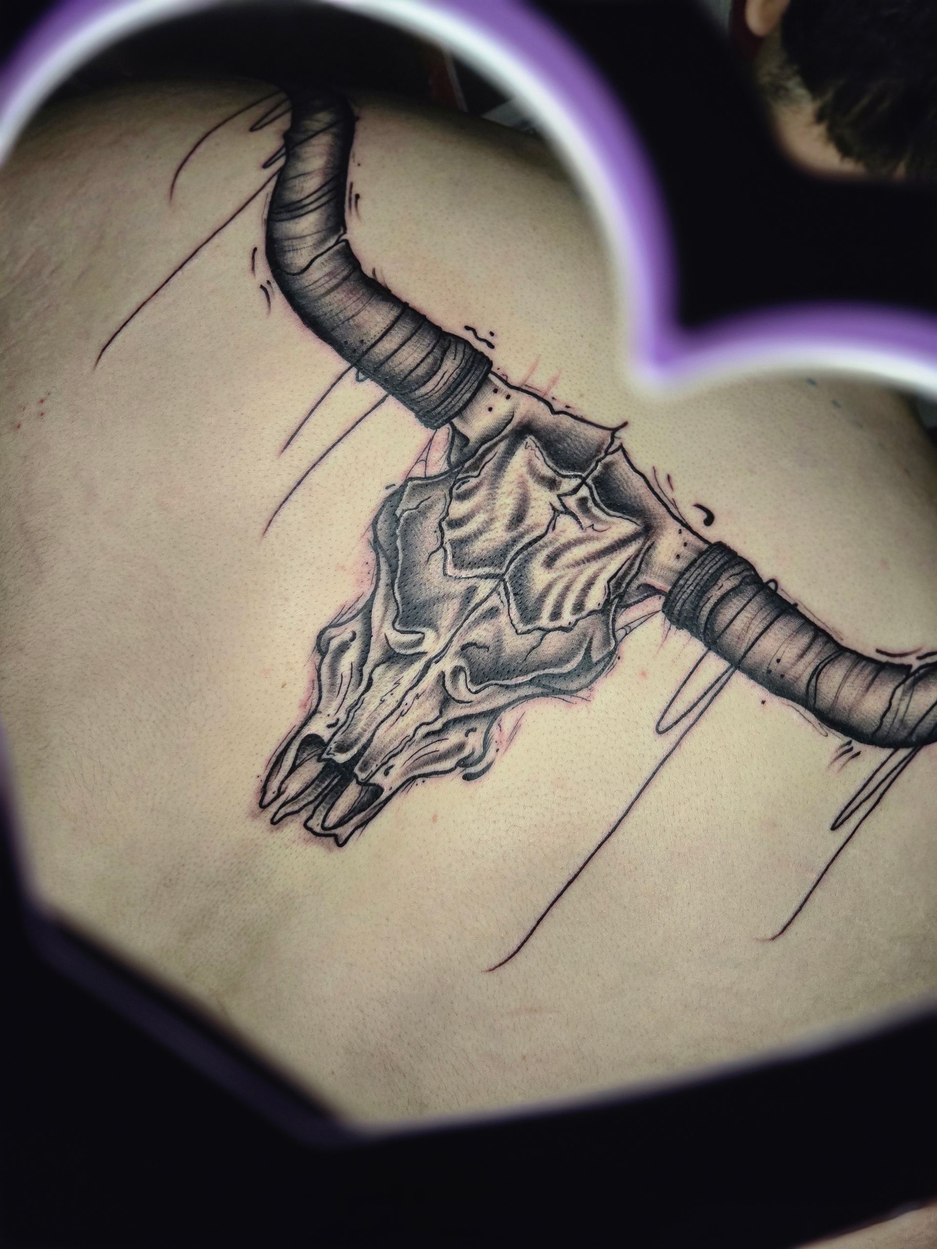 Tattoo of a bull skull with large horns on a person's back.