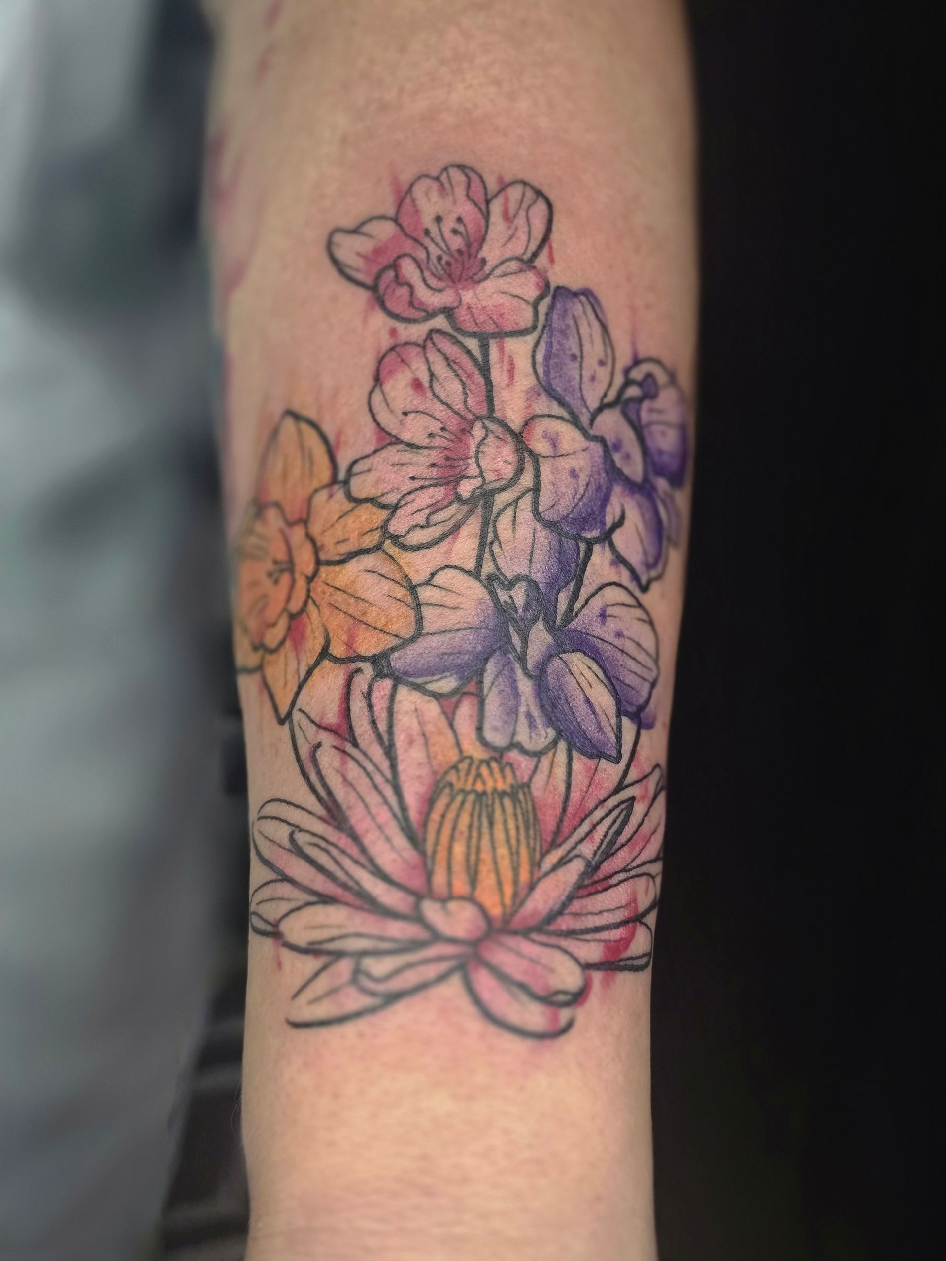Floral tattoo on arm with pink, purple, and yellow blossoms.