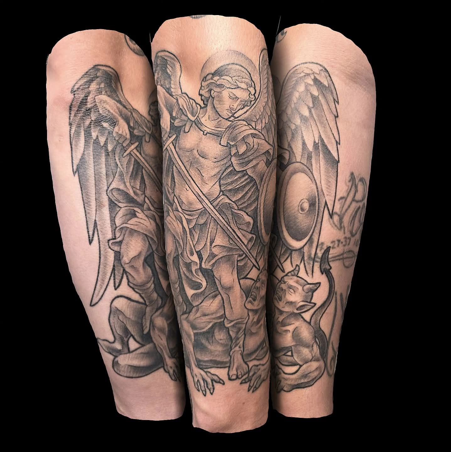 Tattoo of Archangel Michael with sword and shield, slaying a devil. Black and grey shading.