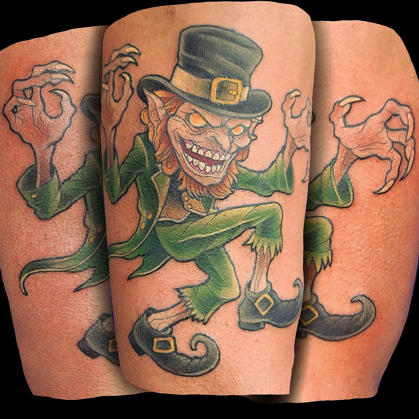Tattoo of a leprechaun with a menacing expression, wearing a green suit and hat, with claws.