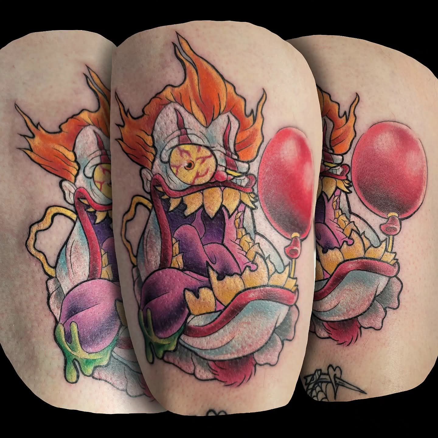 Tattoo of a scary clown with red hair, wide open mouth, red balloons, and green slime.