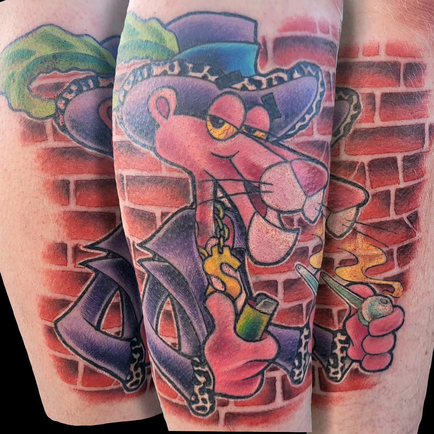 Pink Panther tattoo in a purple suit and hat, smoking a pipe, set against a brick wall.