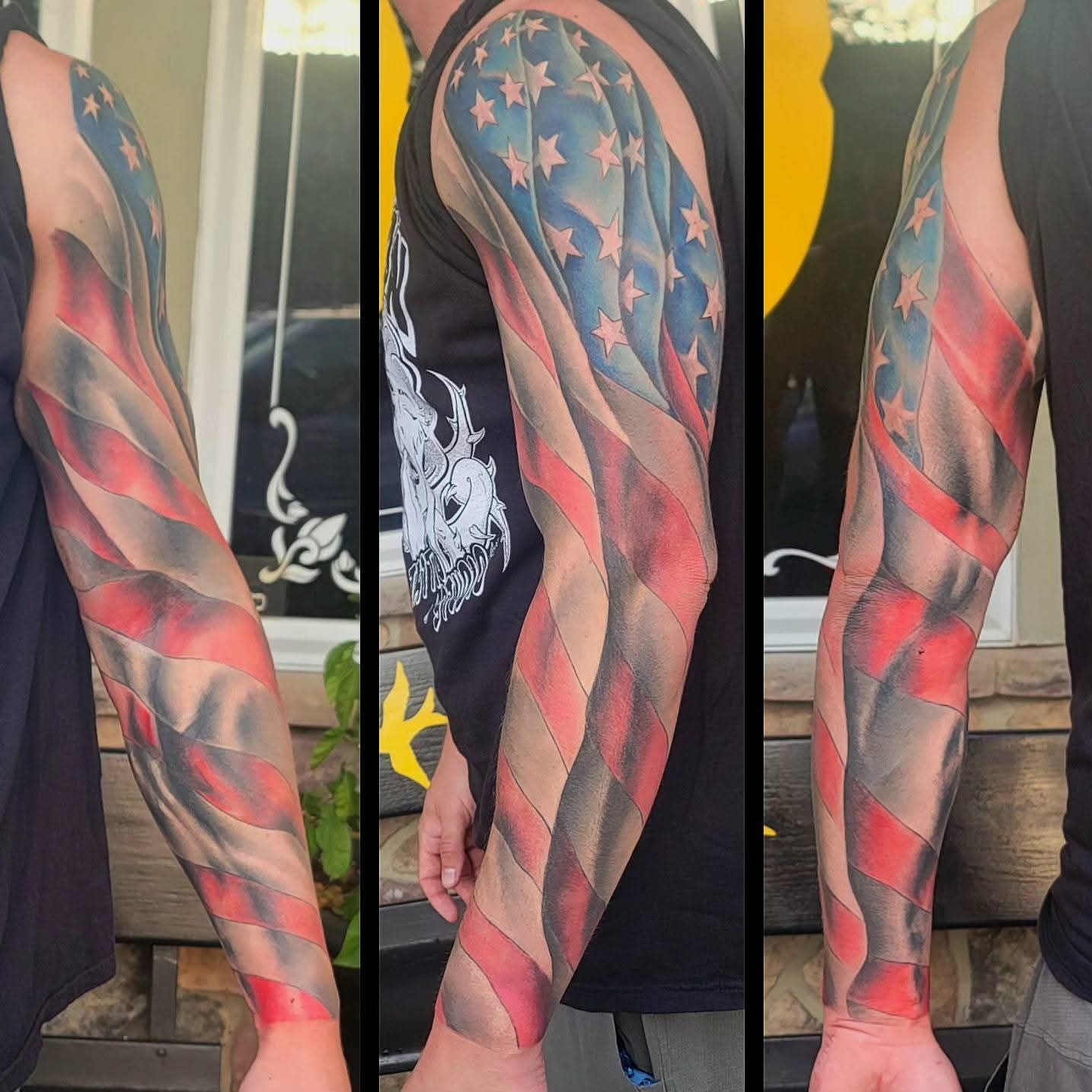 Tattoo of a waving American flag covering an arm, in red, white, blue, and grey.