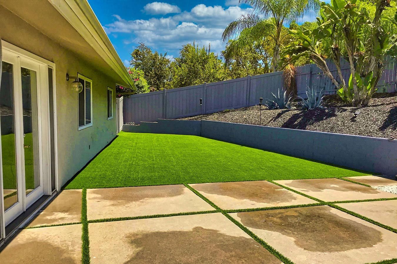 A house with a large lawn and a patio in front of it.