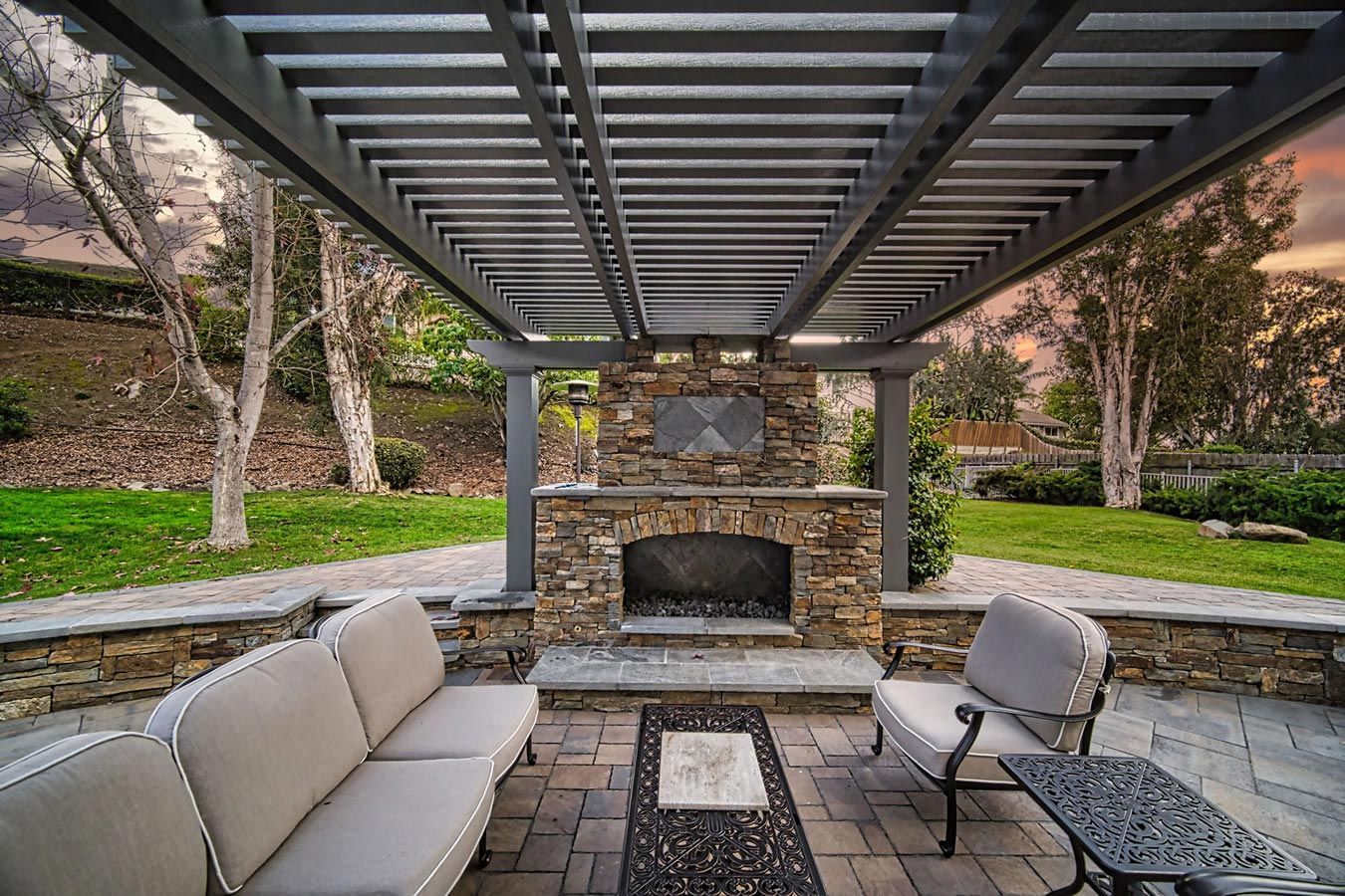 A patio with a fireplace and a couch under a pergola.