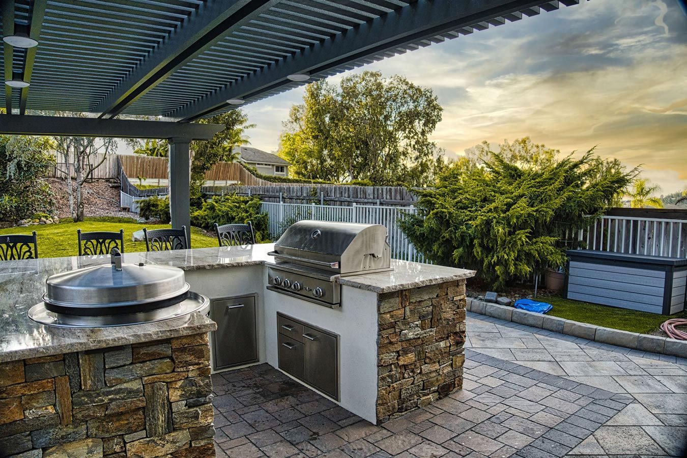 A large outdoor kitchen with a grill and a pergola.