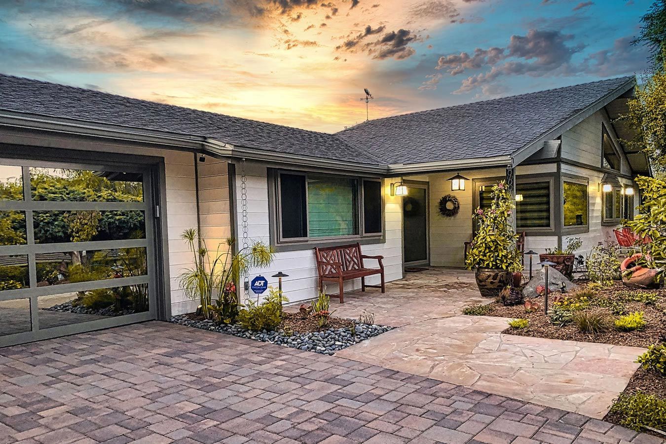 The front of a house with a brick driveway and a glass garage door.