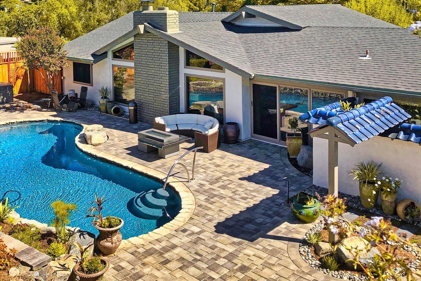 An aerial view of a house with a large swimming pool and hot tub.