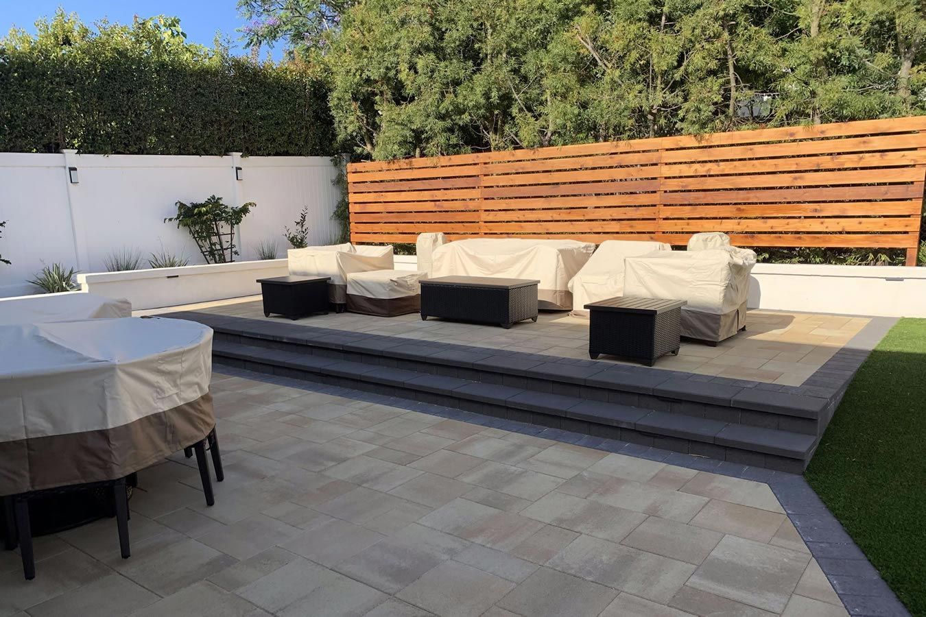 A patio with a table and chairs and a wooden fence.
