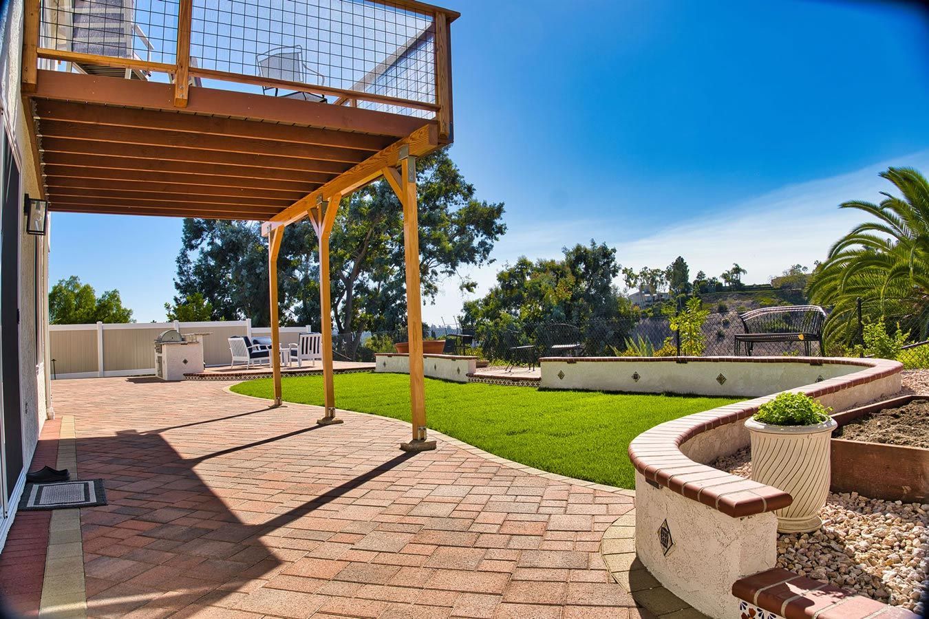 A patio with a wooden deck overlooking a lush green yard