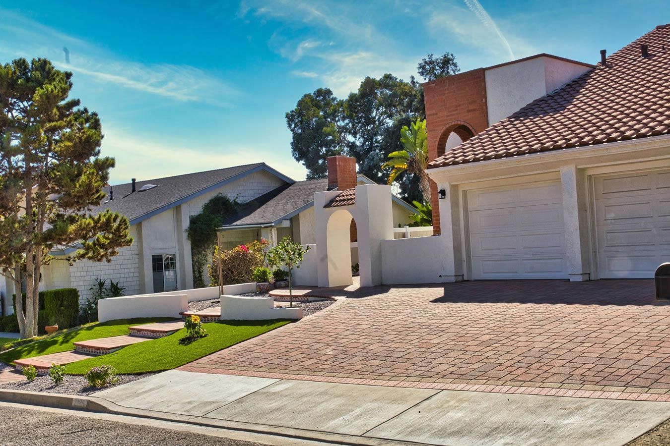 A white house with a brick driveway in front of it.