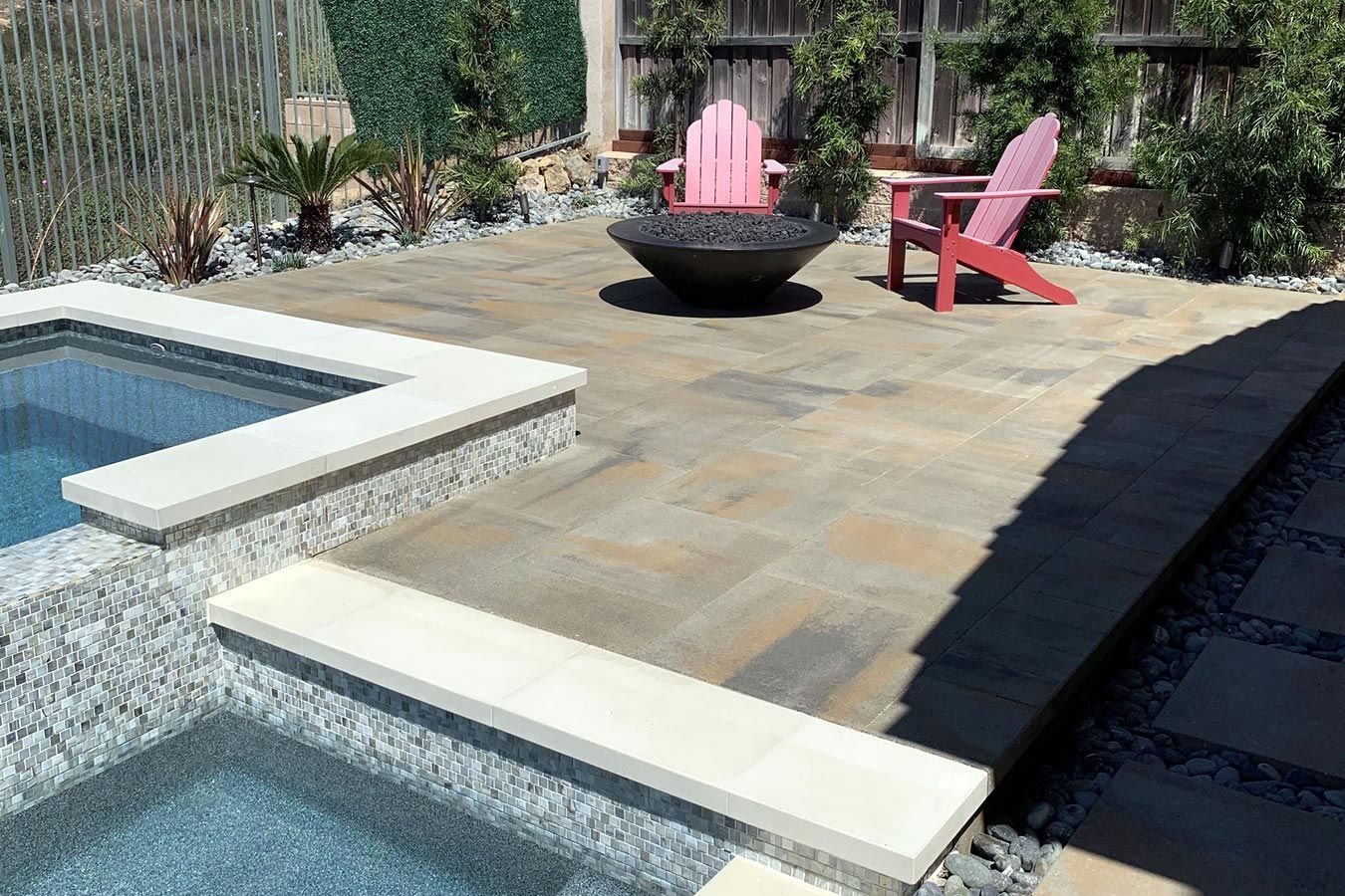 A pink chair is sitting on a patio next to a pool.